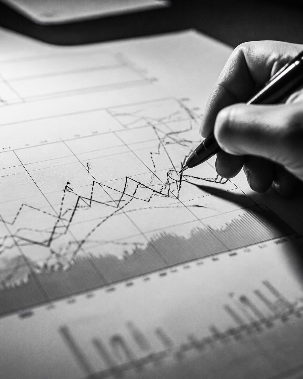 Hand annotating a printed performance chart in black and white